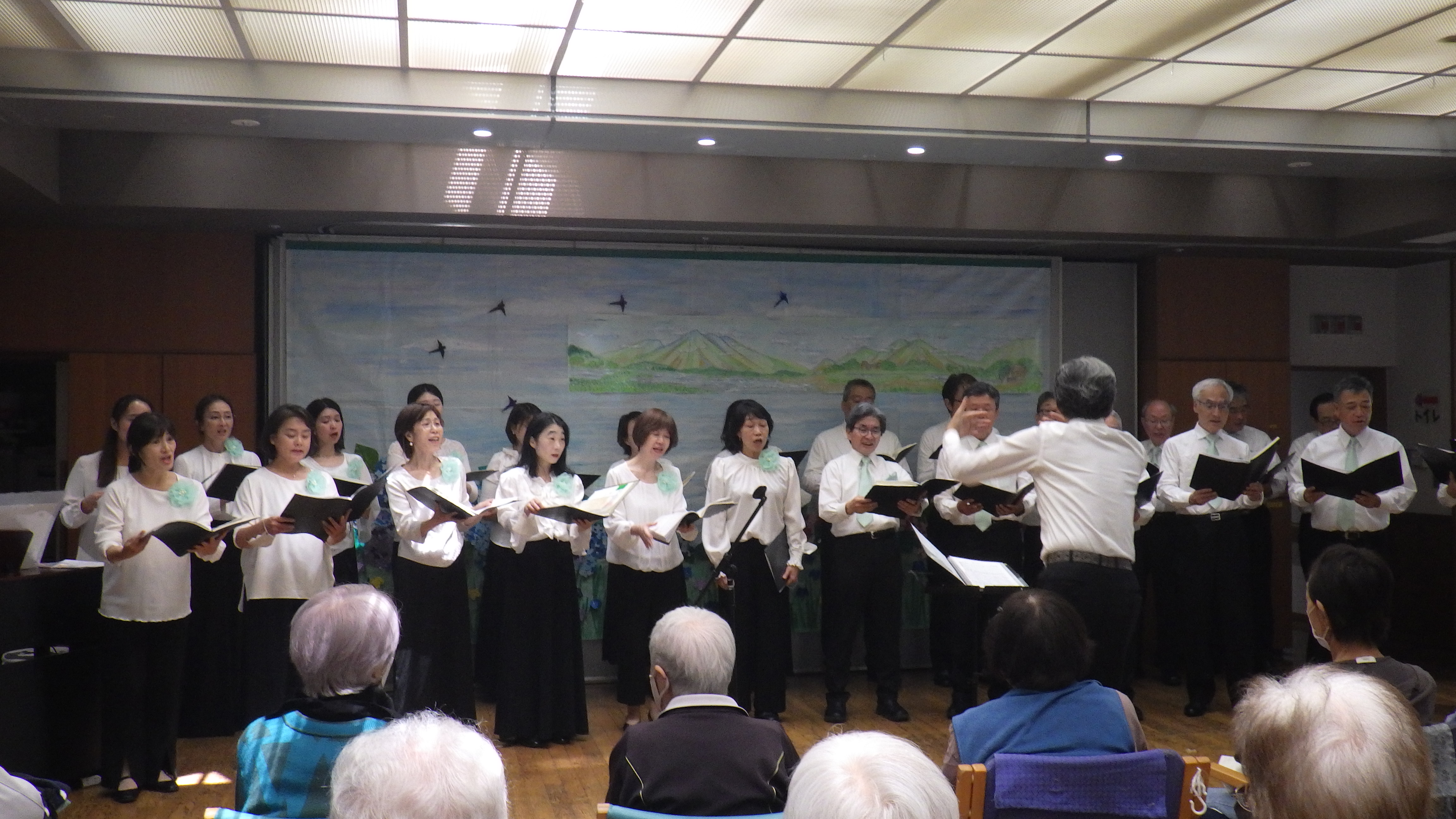 介護施設での合唱会。入居者が観客として合唱団の演奏を楽しんでいる。